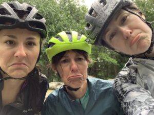 three women cyclists frowning in the rain