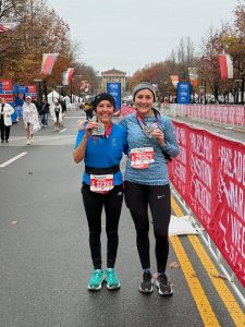 two women holding up medals after running race